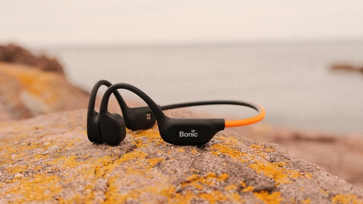 Waterproof open ear headset on rocks illustrating can you swim with bone conduction headphones.