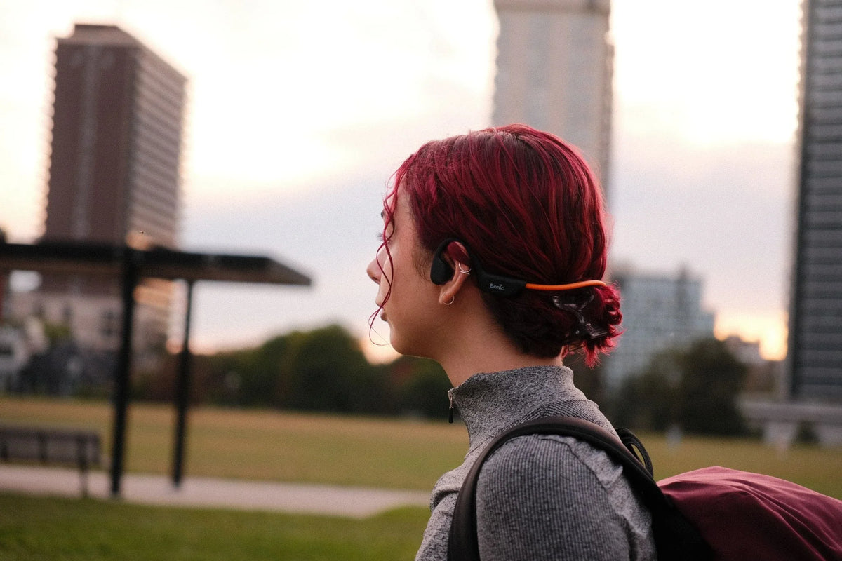 Woman wearing open-ear headphones outdoors exploring are bone conduction headphones safe.